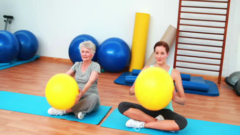 Trainer-and-elderly-client-raising-exercise-balls-