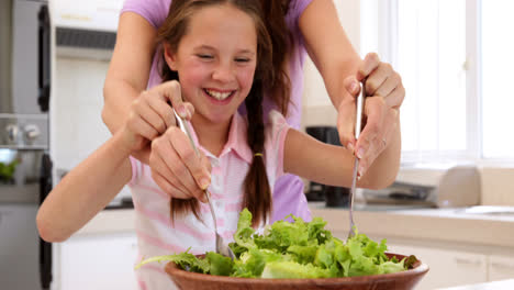 Mother-showing-her-cute-daughter-how-to-toss-a-salad