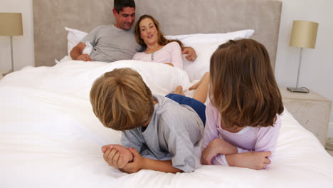 Süße-Eltern-Und-Kinder-Liegen-Im-Bett-Und-Reden