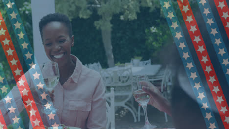Animation-of-stripes-with-stars-over-happy-african-american-women-drinking-wine-in-garden