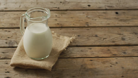 Video-of-glass-jug-of-milk-on-wooden-background