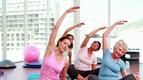 Smiling-women-doing-yoga-in-fitness-studio
