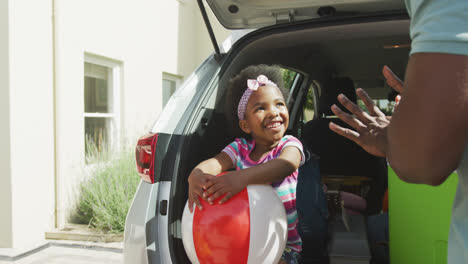 Happy-african-american-family-packing-car-with-beach-balls-on-holiday