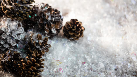 Snow-falling-over-multiple-pine-cones-on-snow-on-wooden-surface