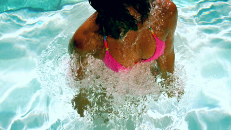Happy-woman-in-pink-bikini-shaking-wet-hair-in-swimming-pool