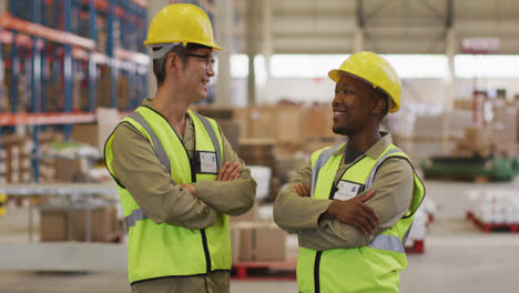 Portrait-of-diverse-male-workers-wearing-safety-suits-and-smiling-in-warehouse