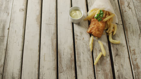 Video-of-wrapped-fish-and-chips-with-dip,-on-rustic-table-top-with-copy-space