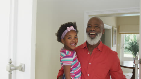 Porträt-Eines-Glücklichen-älteren-Afroamerikanischen-Großvaters,-Der-Seine-Winkende-Enkelin-Trägt