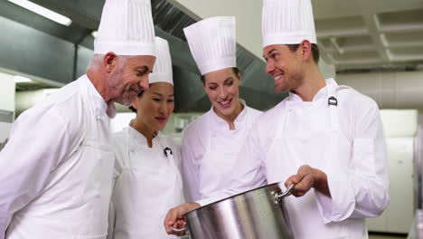 Chef-showing-colleagues-contents-of-large-pot