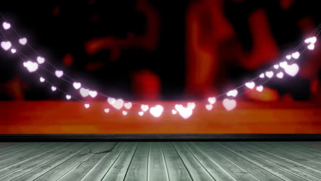 Glowing-pink-heart-shaped-fairy-light-decoration-hanging-over-wooden-plank