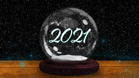 Animation-of-snow-falling-over-snow-globe-with-2021-text-on-black-background