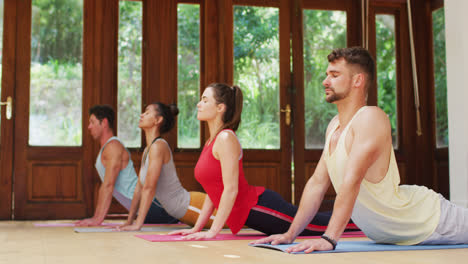 Heterogene-Gruppe-In-Yoga-Position-Dehnt-Sich-Auf-Matten-Während-Des-Yoga-Kurses-Im-Fitnessstudio