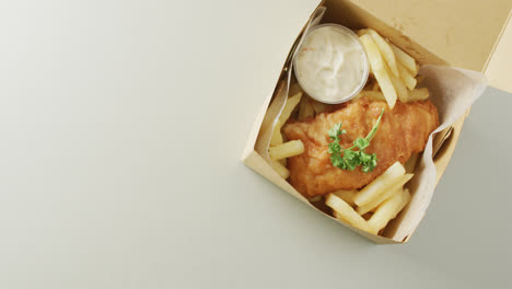 Video-of-fish-and-chips-with-dip-in-takeaway-food-box,-with-copy-space-on-white-background