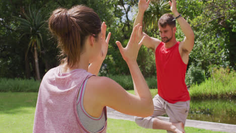 Caucasian-female-yoga-instructor-practicing-yoga-with-caucasian-man-in-park