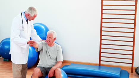 Smiling-doctor-helping-patient-move-his-arm-and-shoulder