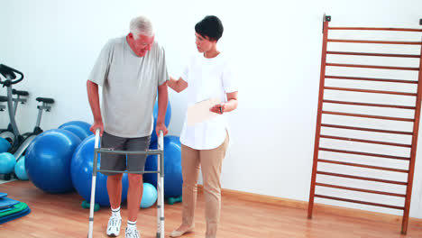 Smiling-physiotherapist-helping-patient-walk-with-walking-frame