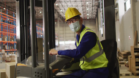 Portrait-of-asian-male-worker-wearing-safety-suit-and-face-mask-in-warehouse