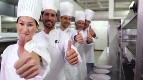Smiling-chefs-standing-in-a-row-giving-thumbs-up