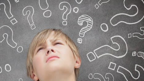 Animation-of-thoughtful-caucasian-boy-looking-up,-with-question-marks-on-chalkboard