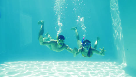 Happy-couple-jumping-into-swimming-pool-wearing-snorkels-and-holding-starfish