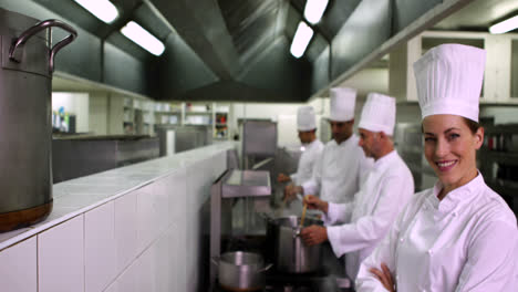 Chefs-working-at-the-stove-with-one-smiling-at-camera