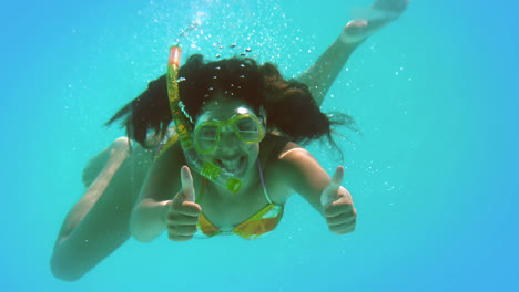 Happy-brunette-wearing-snorkel-underwater-showing-thumbs-up