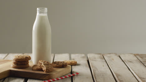Video-of-glass-bottles-of-milk-and-cookies-on-wooden-table-on-white-background