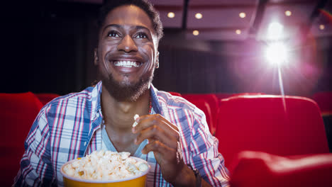 Animation-of-happy-african-american-man-eating-popcorn-in-cinema