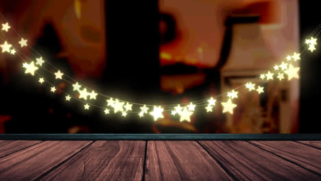 Glowing-yellow-star-shaped-fairy-light-decoration-hanging-over-wooden-plank