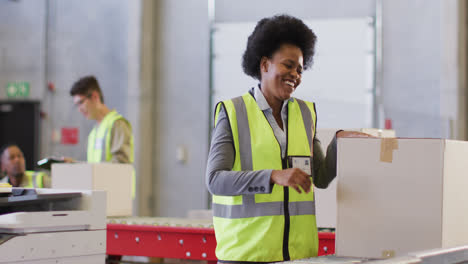 Portrait-of-african-american-female-worker-wearing-safety-suit-and-smiling-in-warehouse
