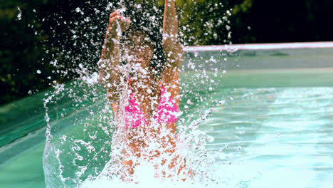 Happy-woman-in-pink-bikini-splashing-at-camera-in-swimming-pool