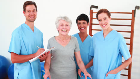 Elderly-woman-smiling-and-talking-with-her-physical-rehab-team