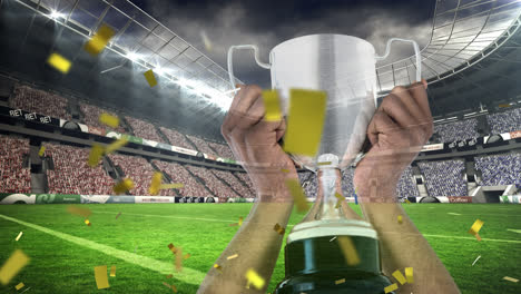 Animation-of-confetti-falling-over-caucasian-man-holding-silver-cup-in-sports-stadium