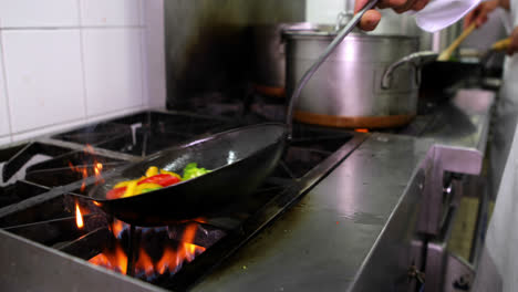 Chef-frying-vegetables-in-a-wok-and-adding-ladle-of-water