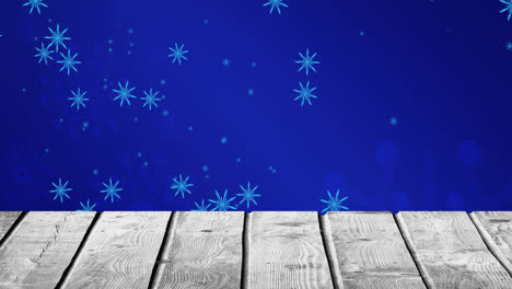 Animation-of-falling-snowflakes-on-blue-background-and-wooden-floor