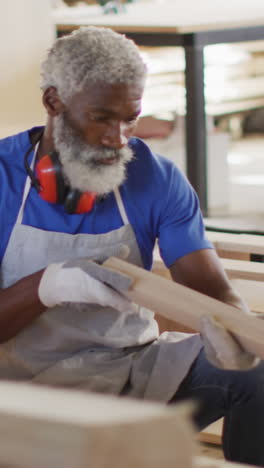 Afroamerikanischer-Handwerker-Inspiziert-Holz-In-Einer-Werkstatt