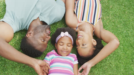 Porträt-Eines-Glücklichen-Afroamerikanischen-Paares-Mit-Ihrer-Tochter,-Die-Im-Garten-Liegt