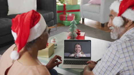 Happy-african-american-senior-couple-on-laptop-video-call-with-family-at-christmas-time