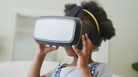 Lächelndes-Afroamerikanisches-Mädchen,-Das-Im-Wohnzimmer-Mit-Einem-VR-Headset-Spielt