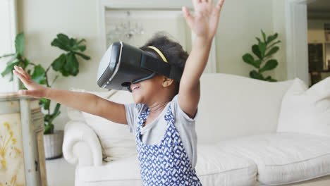 Smiling-african-american-girl-playing-with-vr-headset-in-living-room
