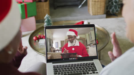 Diverse-senior-female-friends-using-laptop-for-christmas-video-call-with-happy-santa-on-screen