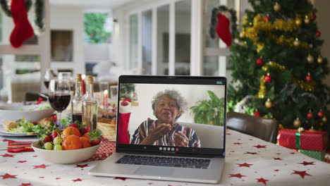 Glückliche-Afroamerikanische-Seniorin-Mit-Laptop,-Die-Auf-Dem-Weihnachtstisch-Liegt