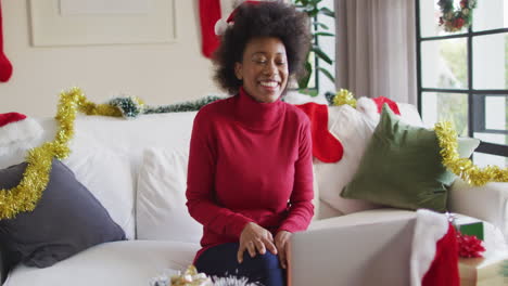 Feliz-Mujer-Afroamericana-Con-Sombrero-Navideño-De-Papá-Noel-Haciendo-Videollamadas-Con-Laptop,-Cámara-Lenta