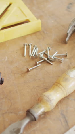 Various-tools-and-nails-are-scattered-on-a-wooden-surface