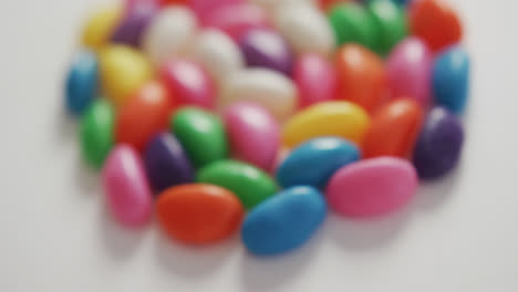 Video-of-close-up-of-multi-coloured-sweets-forming-circle-over-white-background