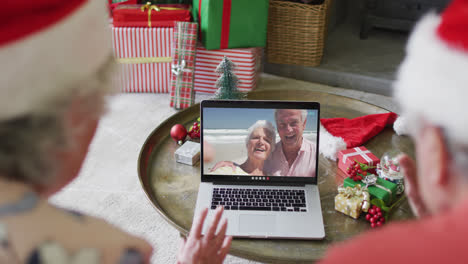 Senior-caucasian-couple-using-laptop-for-christmas-video-call-with-happy-couple-on-screen