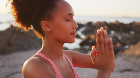 Nahaufnahme-Einer-Afroamerikanischen-Frau,-Die-Yoga-Praktiziert-Und-Auf-Den-Felsen-In-Der-Nähe-Des-Meeres-Meditiert