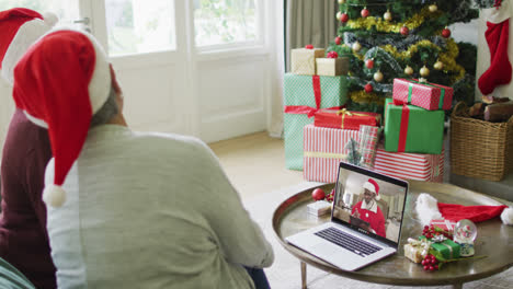 Diverse-senior-female-friends-using-laptop-for-christmas-video-call-with-santa-on-screen
