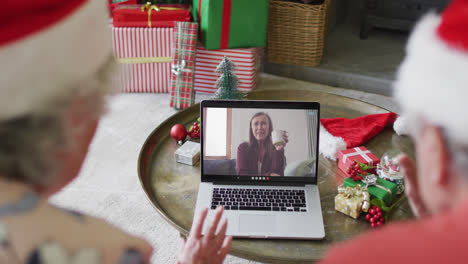 Senior-caucasian-couple-using-laptop-for-christmas-video-call-with-happy-woman-on-screen