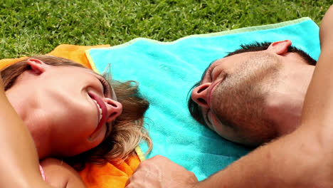 Sexy-couple-lying-on-beach-towels-on-holidays-